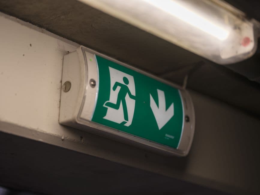 A stairwell ceiling light fitting with a fresh tube installed, the foot of a stepladder below.