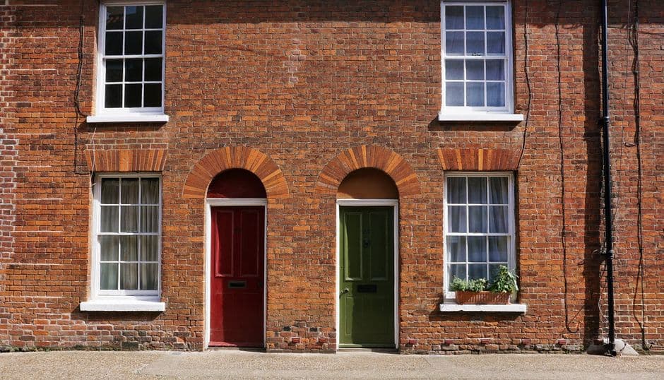 A brick apartment building photographed straight on in flat morning light, rows of identical windows above a plain entrance.