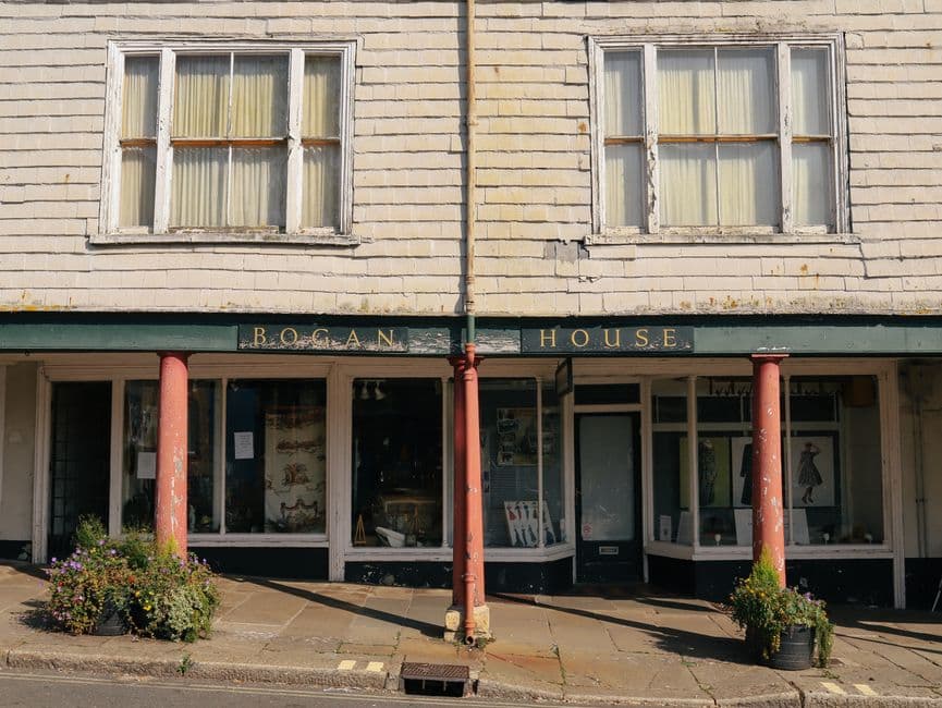 A small mixed-use building with a shuttered shop unit at street level and flats on the floors above.