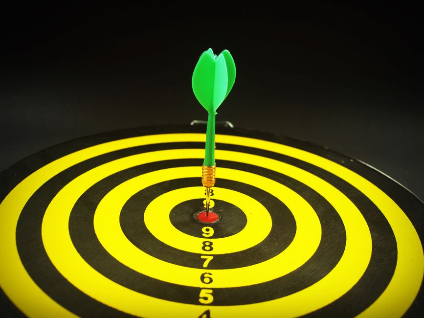 A dart standing in the centre ring of a dartboard, cropped close to the numbered rings.
