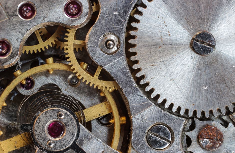 Close view of a machined brass and steel gear train inside a stripped mechanism.