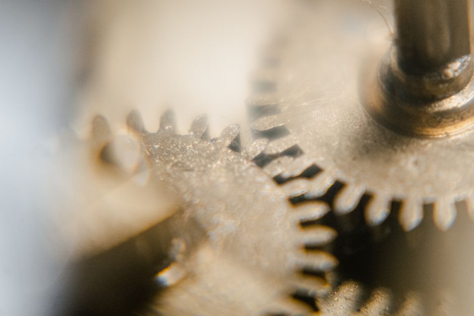 A soft-focus macro of two meshed gear wheels in pale daylight.